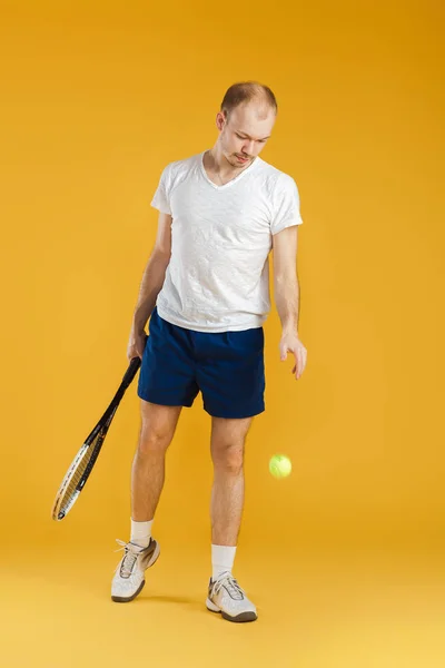 Jovem tenista joga tênis no fundo amarelo — Fotografia de Stock