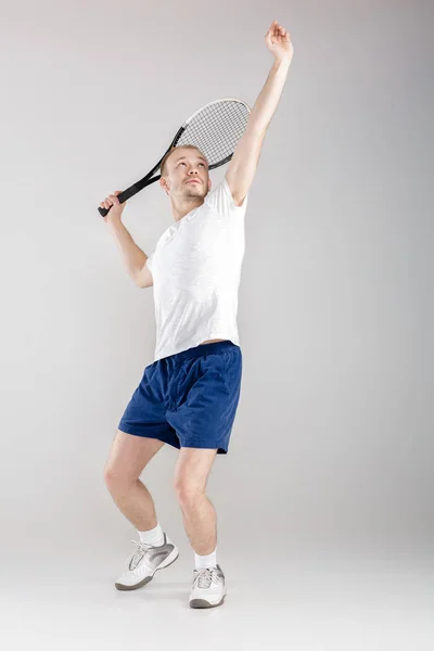 Jovem tenista joga tênis em fundo cinza — Fotografia de Stock