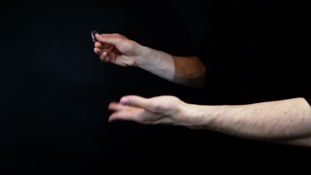 Iluzjonista pokazuje podstęp monety na czarnym tle — Wideo stockowe