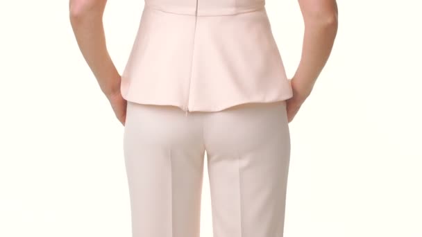 Jovem mulher em um terno rosa de pé com as costas e se vira para a câmera. close-up da cintura — Vídeo de Stock