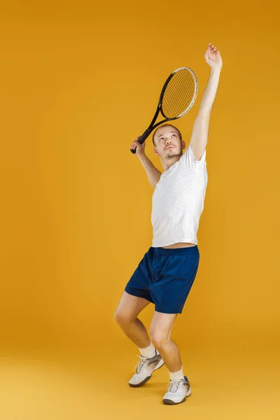 Jovem tenista joga tênis no fundo amarelo — Fotografia de Stock