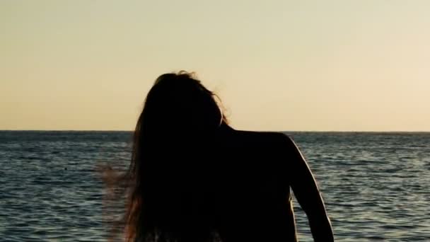 Sziluettjét lány hosszú repülő haj, a háttérben a tenger — Stock videók