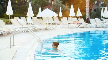 genç esmer kadın bikini ve güneş gözlüğü Yüzme Havuzu güneşli yaz günü alır.