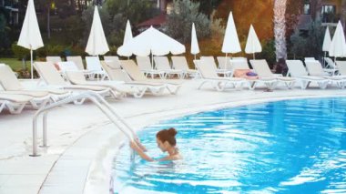 genç esmer kadın bikini ve güneş gözlüğü Yüzme Havuzu güneşli yaz günü alır.