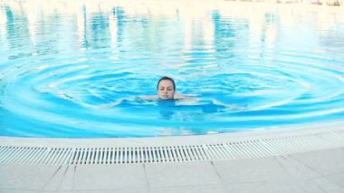 genç esmer kadın bikini ve güneş gözlüğü Yüzme Havuzu güneşli yaz günü alır.