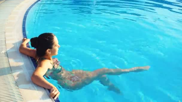 年轻的黑发女人，在池中的一个阳光明媚的夏日比基尼 — 图库视频影像