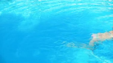 bikini ve güneş gözlüğü genç esmer kadın havuzda güneşli yaz gününde yüzüyor.