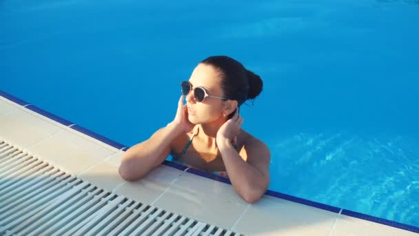 Joven morena en bikini en la piscina en un día soleado de verano — Vídeo de stock