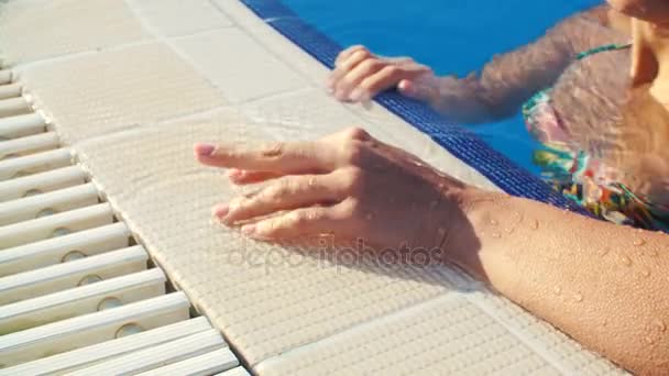 Γυναικείο χέρι στην άκρη της πισίνας στο ηλιόλουστο καλοκαιρινό ημέρα closeup — Αρχείο Βίντεο