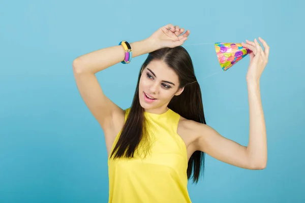 Giovane donna attraente sorridente con cappello di compleanno e fischietto su sfondo blu. festa e festa — Foto Stock