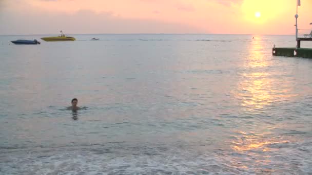 Mooie gebruinde vrouw uit het water op het strand bij zonsondergang — Stockvideo