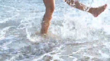 yanık tenli kadın ayak plaj üzerinde. su sıçramasına kum plajındaki okyanusta ayakları üzerinde