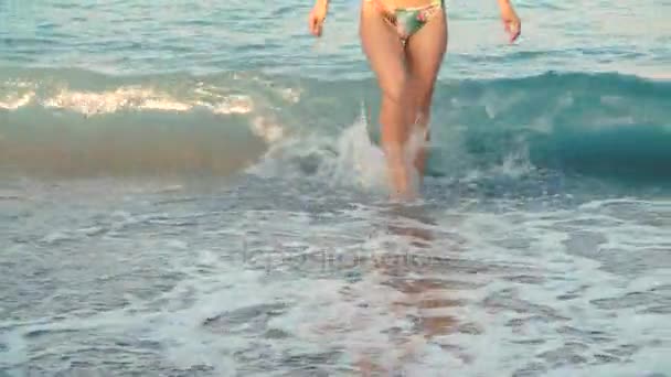 На пляже женщины вытаскивают из воды красивые одуванчиковые ноги. Девушка ходит по морю — стоковое видео