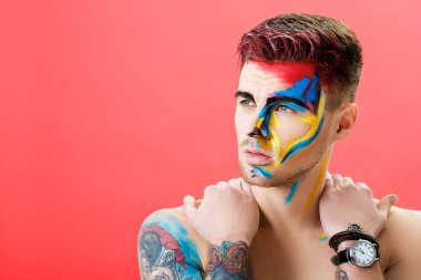 kırmızı bir arka plan üzerinde renkli yüz boyama ile genç adam portresi. Profesyonel makyaj moda. fantezi sanat makyaj