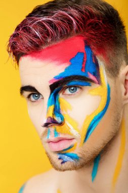 sarı arka plan üzerinde renkli yüz boyama ile genç adam portresi. Profesyonel makyaj moda. fantezi sanat makyaj