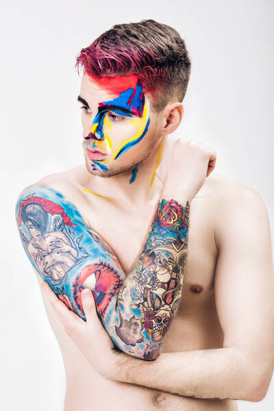 portrait of young attractive man with colored face paint on white background. Professional Makeup Fashion. ffantasy art makeup