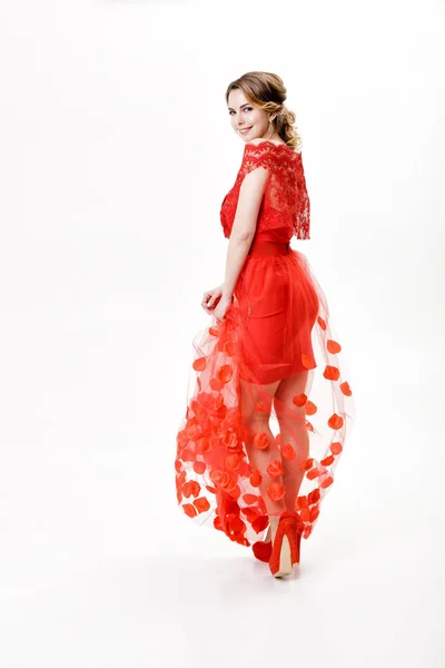 Aantrekkelijke jonge vrouw in avond rode jurk op witte achtergrond — Stockfoto