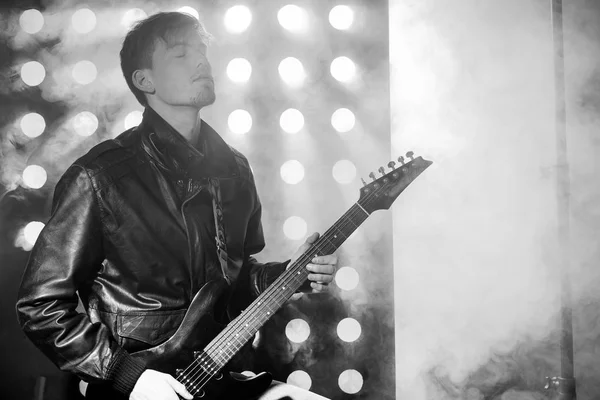 若いロック ミュージシャン演奏エレクトリック ・ ギターと歌の黒と白の写真。スポット ライトの背景のロック スター — ストック写真