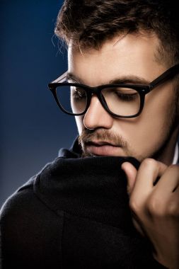 Mavi arka plan gözlüklerle yakışıklı genç adam portresi