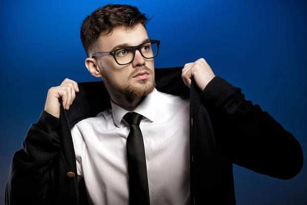 Portrét pohledný mladý muž s brýlemi a bílé tričko na modrém pozadí — Stock fotografie