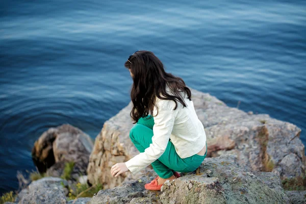 Mujer se sienta en la roca y disfruta de la vista del río — Foto de Stock