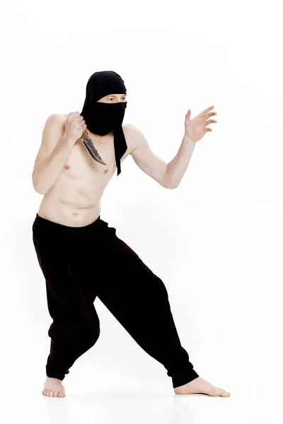Ninja hombre sostiene cuchillo y está listo para atacar sobre fondo blanco —  Fotos de Stock