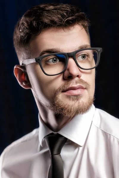 Porträt eines hübschen jungen Mannes mit Brille und weißem Hemd auf dunklem Hintergrund — Stockfoto