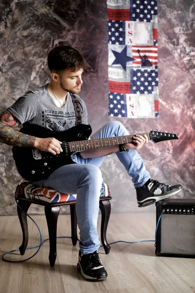 Jovem músico bonito tocando guitarra elétrica no fundo escuro — Fotografia de Stock