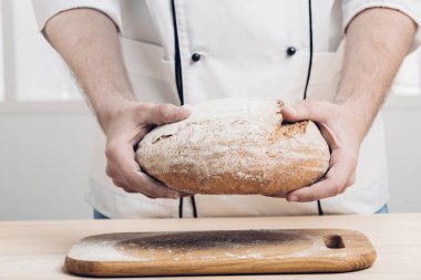 Taze pişmiş ekmek fırıncı ellerinde. yumuşak ışık