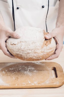 Taze pişmiş ekmek fırıncı ellerinde. yumuşak ışık