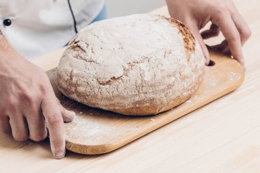 Taze pişmiş ekmek fırıncı, elinde ahşap tahta üzerinde. yumuşak ışık