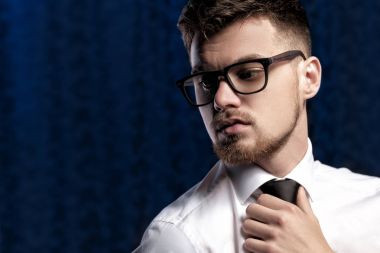 Koyu arka plan üzerinde gözlük ve beyaz gömlek ile yakışıklı genç adam portresi