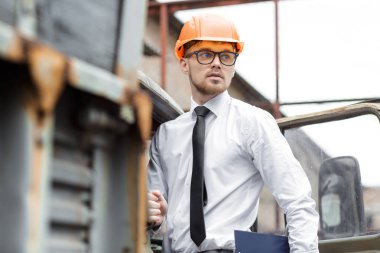 Mühendis Oluşturucu bir kask içinde çizimler inşaat alanında tutar.