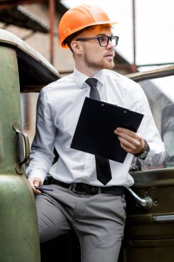 Mühendis Oluşturucu bir kask içinde çizimler inşaat alanında tutar.