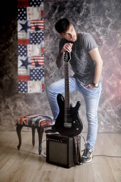 Jovem músico bonito com guitarra elétrica no fundo escuro — Fotografia de Stock