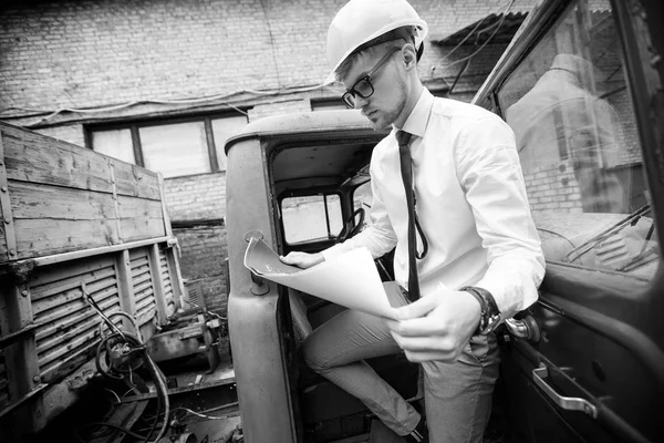 Constructeur ingénieur dans un casque tient des dessins sur le chantier de construction — Photo