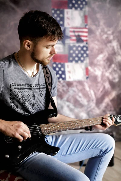 Jovem músico bonito tocando guitarra elétrica no fundo escuro — Fotografia de Stock