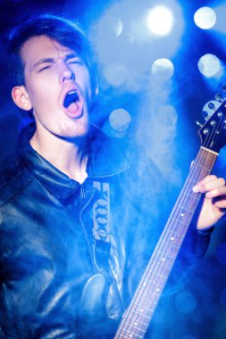 elektro gitar çalarken genç çekici rock müzisyeni. Rock yıldızı Spot arka plan üzerinde
