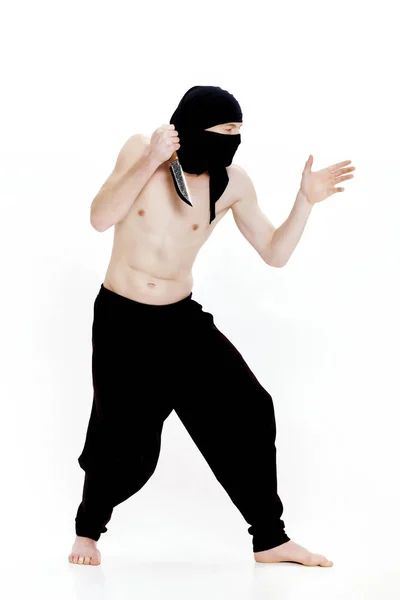 Ninja hombre sostiene cuchillo y está listo para atacar sobre fondo blanco — Foto de Stock