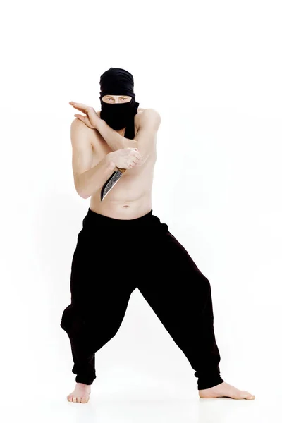 Ninja hombre sostiene cuchillo y está listo para atacar sobre fondo blanco — Foto de Stock