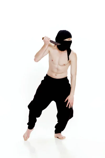 Ninja man holds knife and is ready to attack on white background — Stock Photo, Image