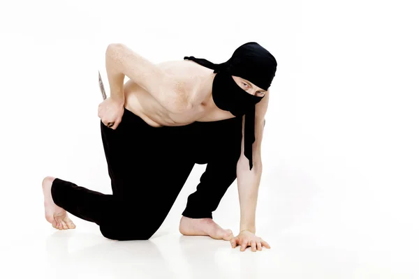 Ninja homem segura faca e está pronto para atacar em fundo branco — Fotografia de Stock
