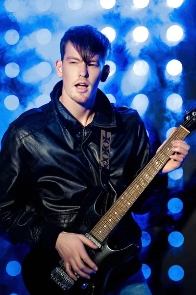 매력적인 젊은 록 음악가 전기 기타 연주와 노래. 스포트 라이트의 배경에 록 스타 — 스톡 사진