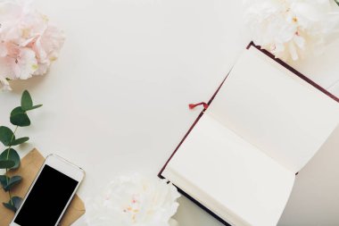 arka planını çiçekler ve telefon üstünde boş defter. Üstten Görünüm. yukarı alay