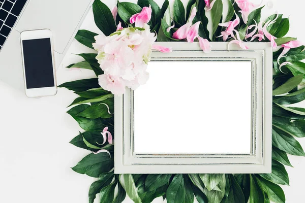 Wooden frame decorated with flowers and leaves, laptop and phone. empty space for text — Stock Photo, Image
