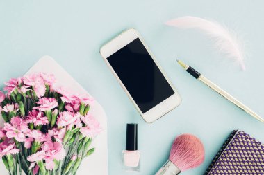 kadınsı düz mavi arka plan, zarf, çiçek, kalem, not defteri ve smartphone womans masaüstünün üst görünümden yatıyordu. yukarı alay