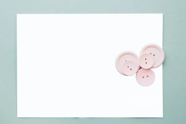 フラット横たわっていたピンクのボタンと青色の背景、トップ ビューに空白の白いシート。モックアップします。 — ストック写真
