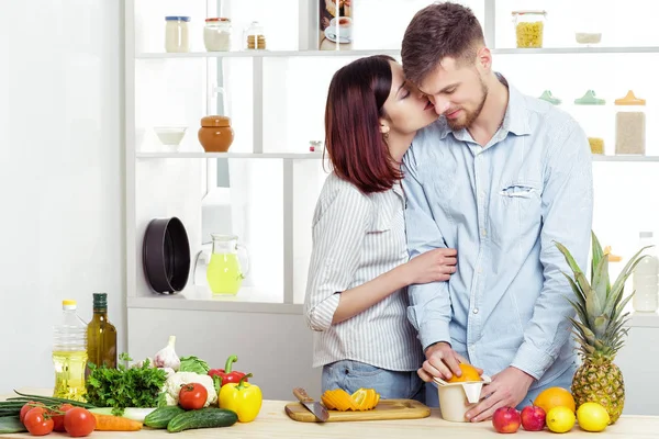 幸福夫妻爱在厨房制作健康从新鲜桔子汁。情侣接吻 — 图库照片