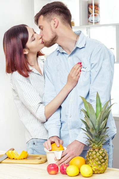 Szczęśliwa para zakochana w kuchni podejmowania zdrowego soku ze świeżych pomarańczy. para jest Całowanie — Zdjęcie stockowe