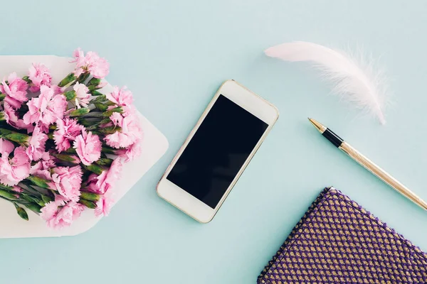 Kadınsı düz mavi arka plan, zarf, çiçek, kalem, not defteri ve smartphone womans masaüstünün üst görünümden yatıyordu. yukarı alay — Stok fotoğraf